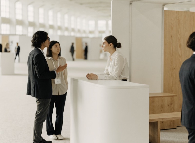 A clean modern trade show booth with attendees talking to a representative.